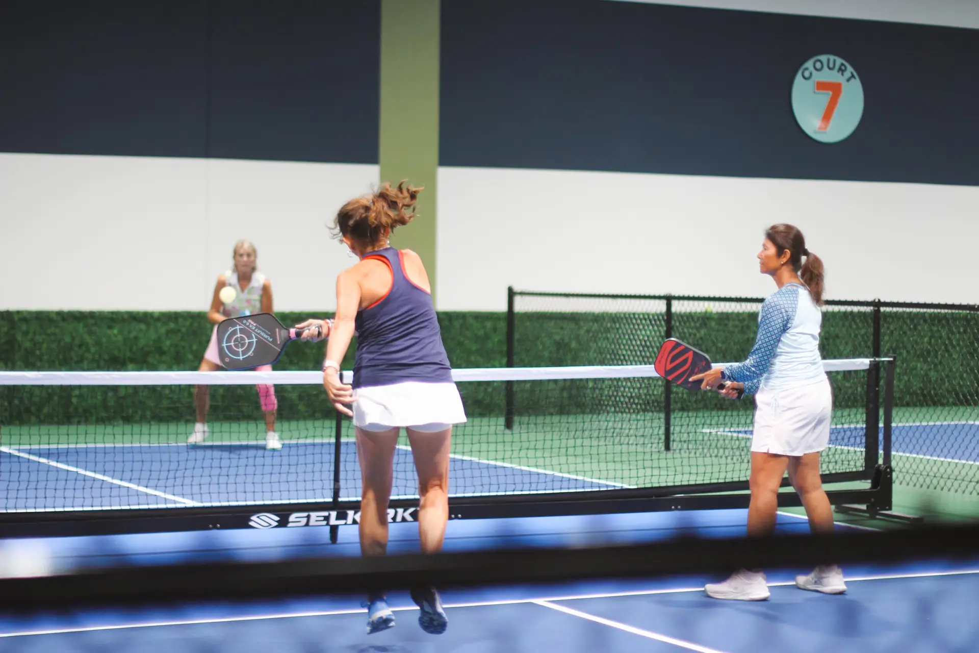 Players volleying on an indoor DiNK’D pickleball court